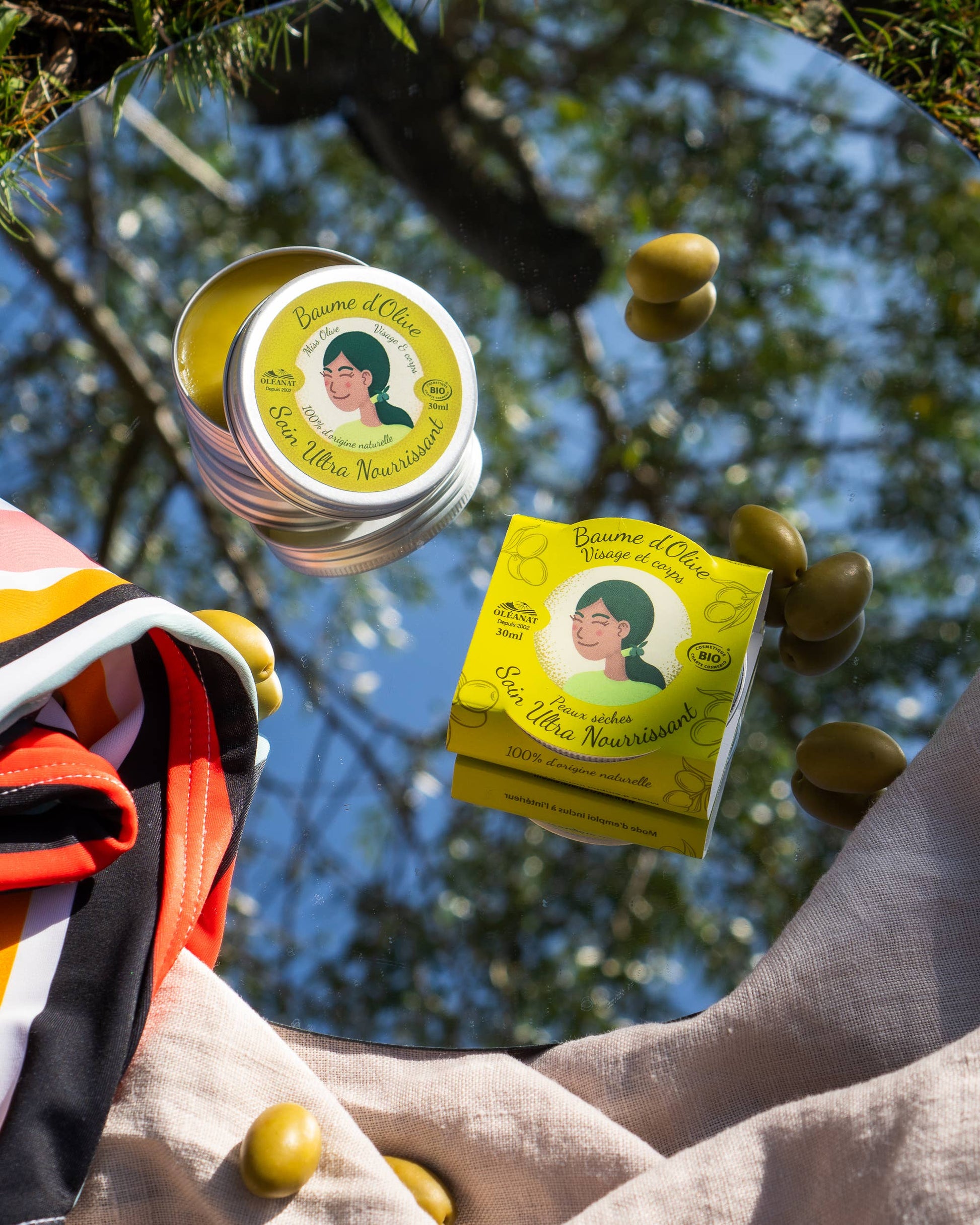 Fliegende Bio-Olivenbalsam-Dosen von Oléanat mit Oliven – kreative Darstellung natürlicher Pflege mit Olivenöl