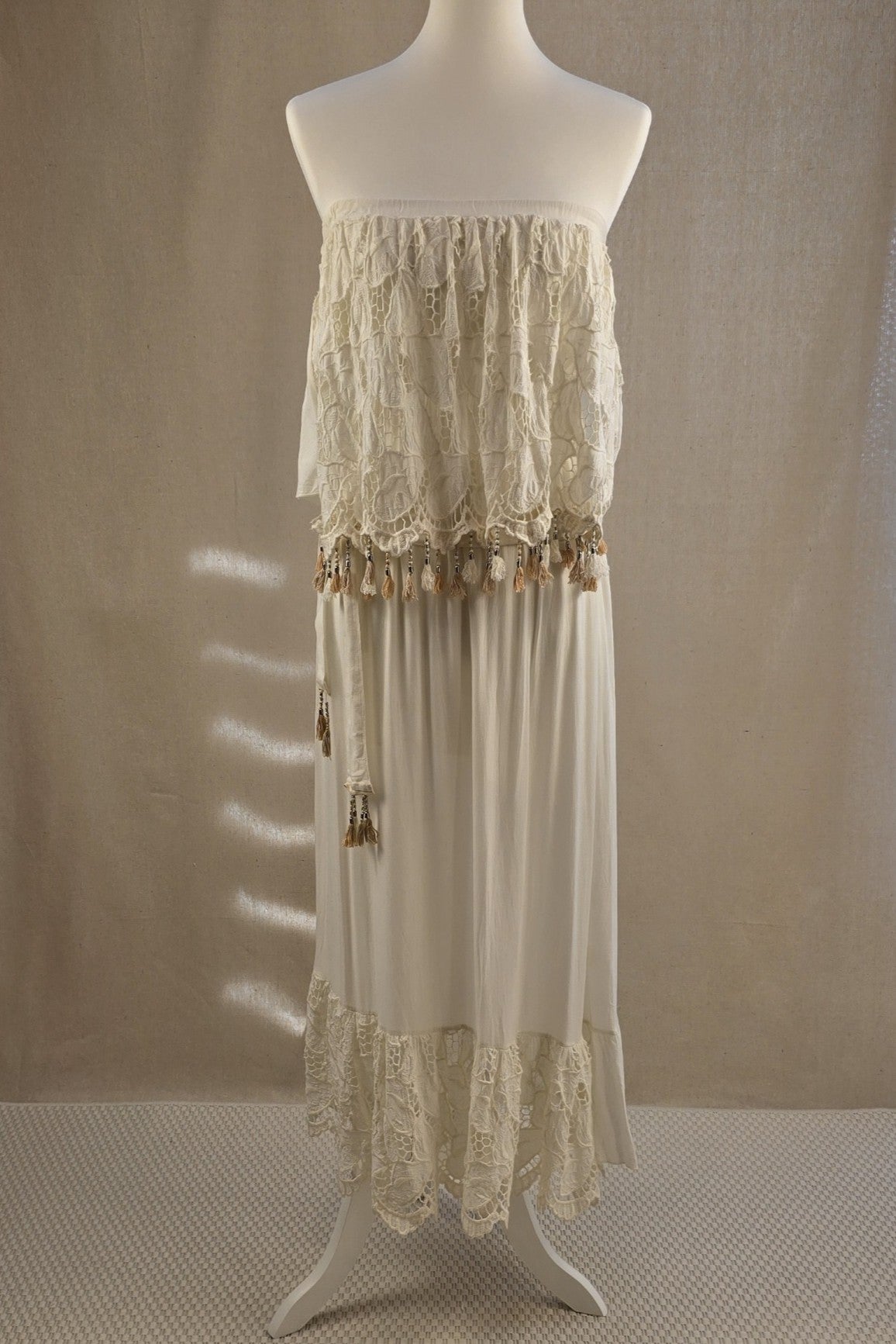 Boho-Kleid von Laurie & Joe in Creme mit Spitzenbesatz und Perlen, vorne getragen mit passendem Bindegürtel im selben Stoff.