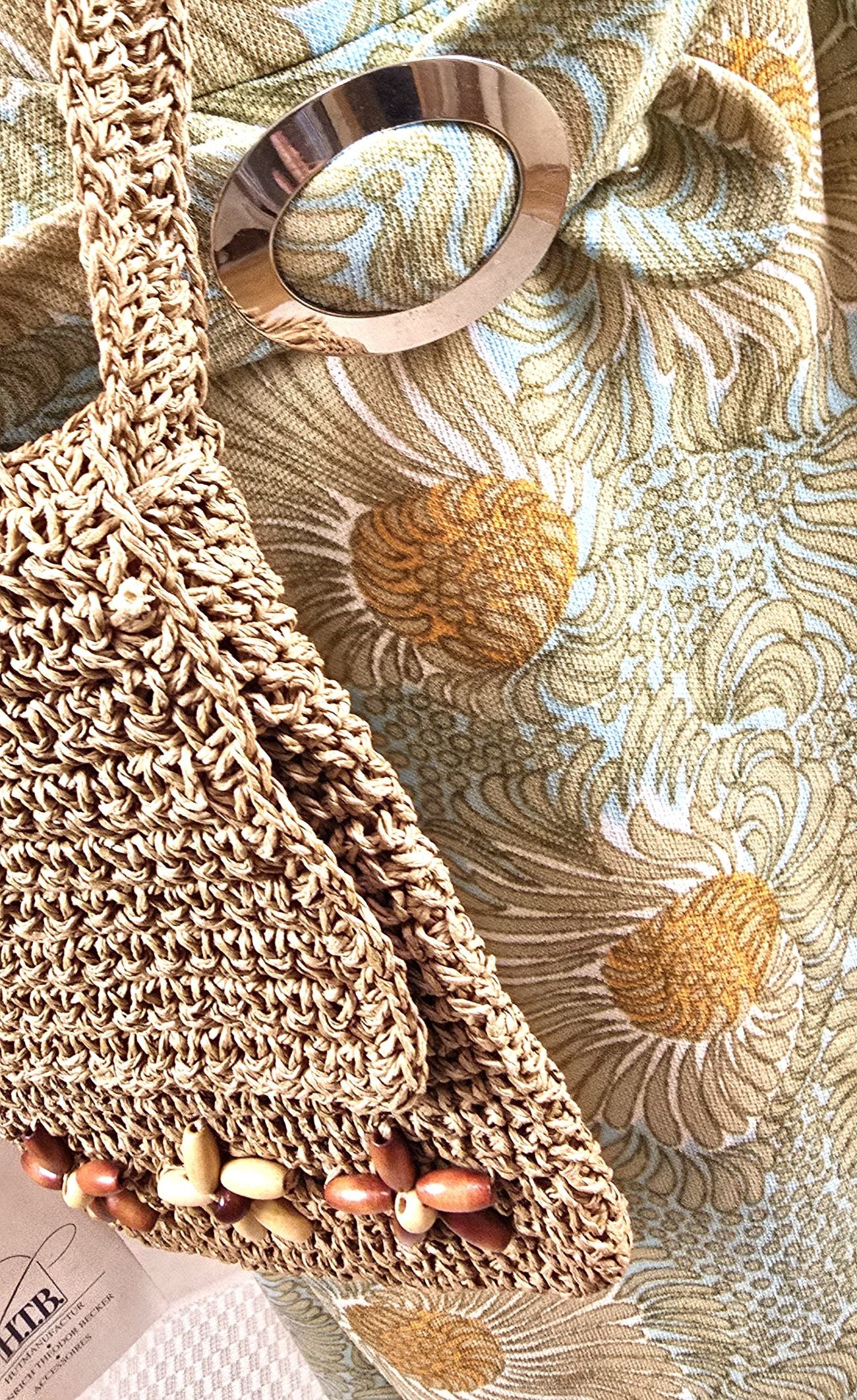 Detailaufnahme des floralen Stoffmusters vom Retro-Sommerkleid aus Trevira 2000, kombiniert mit der Vintage-Basttasche der H.T.B. Hutmanufaktur