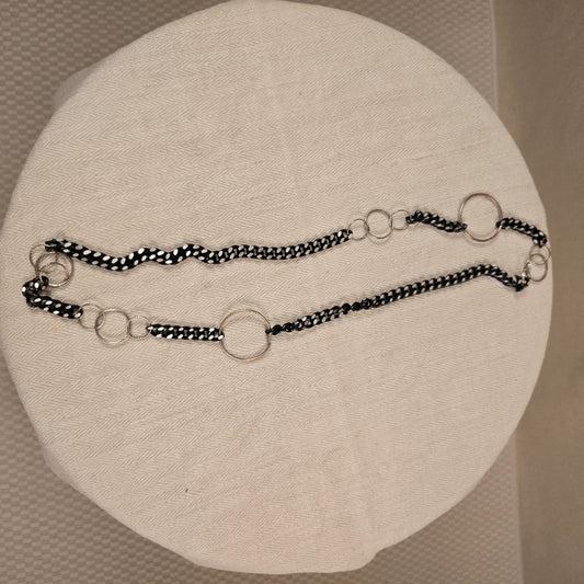 Halskette „Chain Reaction“ mit silberfarbenen Gliedern und schwarzem Stoffband mit weißen Punkten – auffälliger, flexibler Materialmix