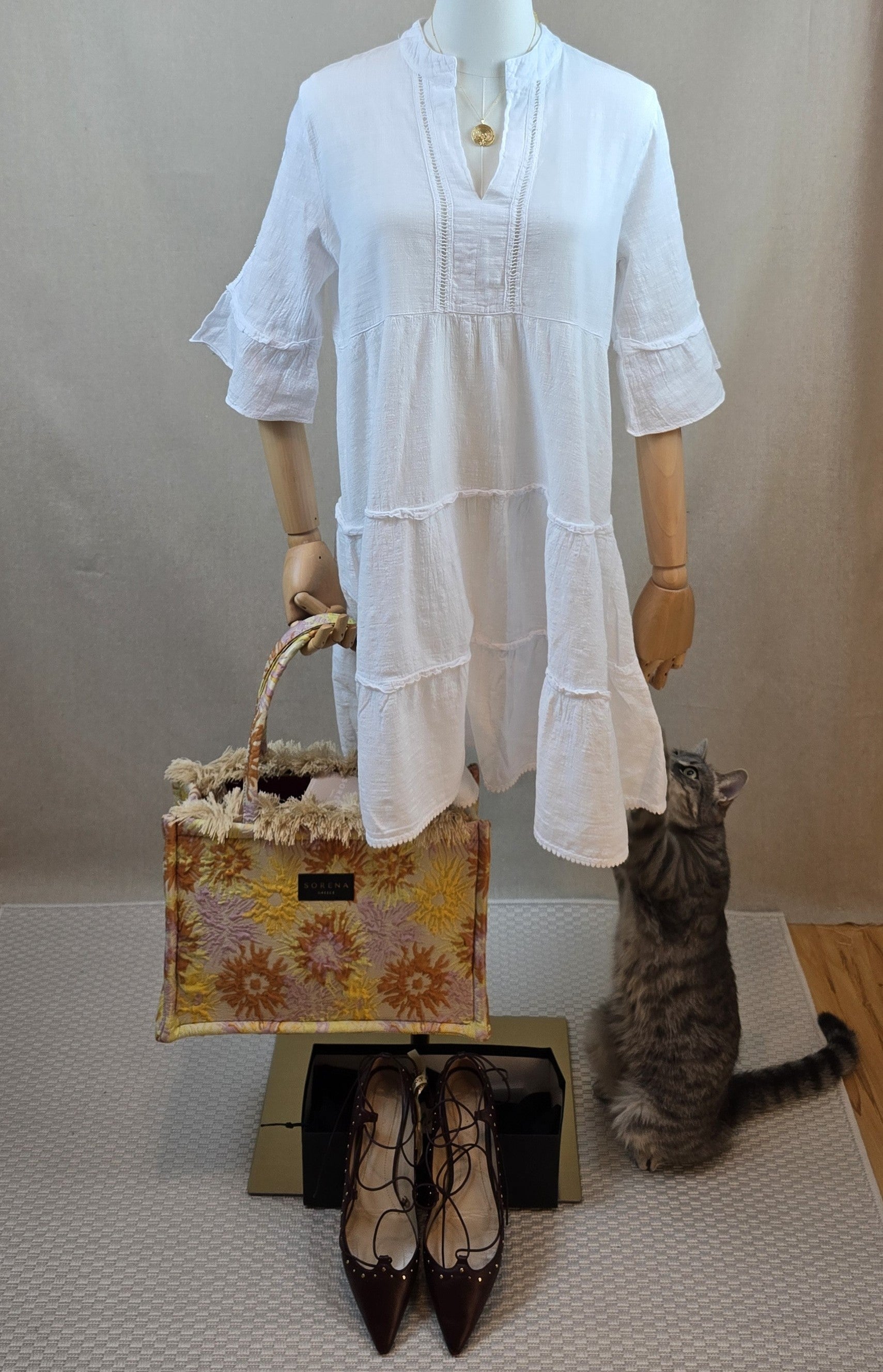 Weißes Tunikakleid aus Baumwollgaze kombiniert mit Sorena-Tasche, vergoldeter Kette und bordeauxfarbenen Vintage-Ballerinas