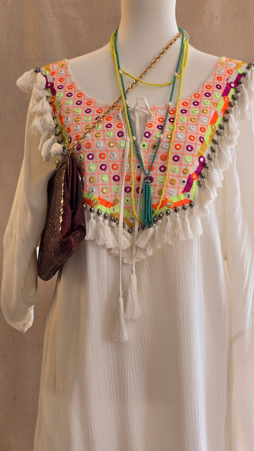 Detailansicht des Tunika-Kleids von Miss June mit farbiger Stickerei, Spiegel-Elementen, Fransen sowie Vintage-Tasche und Statement-Ketten