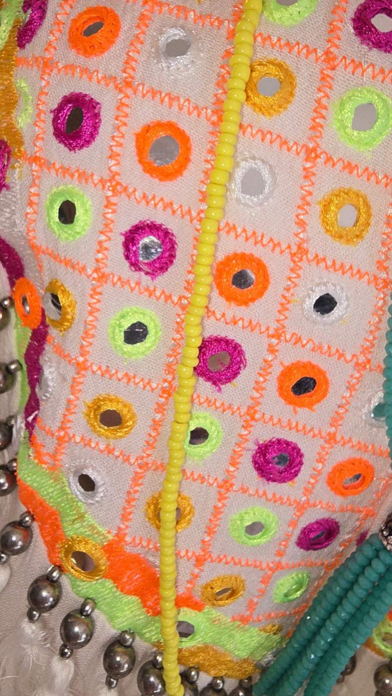 Detailaufnahme des Tunika-Kleids von Miss June mit farbiger Stickerei und integrierten kleinen Spiegel-Applikationen – kombiniert mit Tasche und Ketten im Vintage-Stil