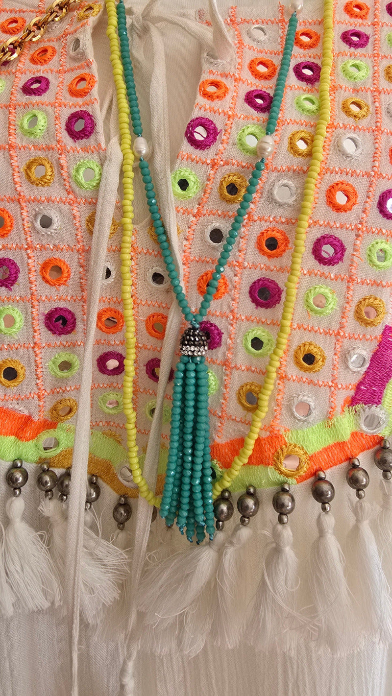 Detailaufnahme des Tunika-Kleids von Miss June Paris mit bunter Stickerei, kleinen Spiegel-Elementen, feinen Fransen sowie kombiniert mit einer strukturierten Vintage-Ledertasche und auffälligen Statement-Ketten im Ethno-Stil