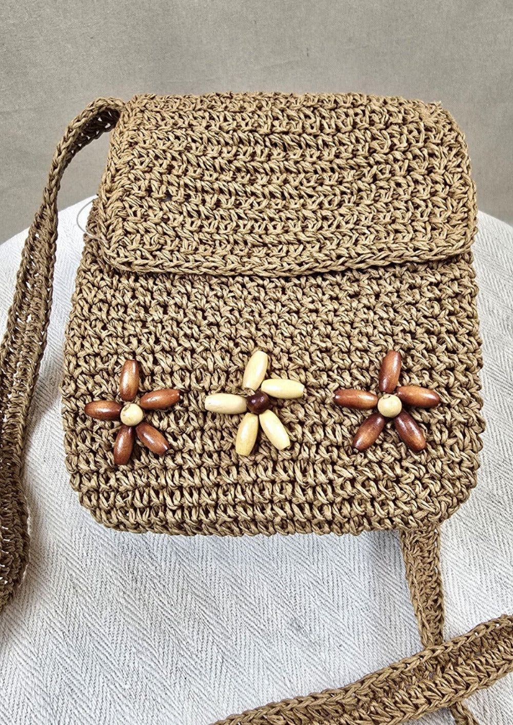 Vintage-Basttasche der Hutmanufaktur H.T.B., liegend fotografiert auf neutralem Hintergrund – mit Blütendekor und Originaletikett