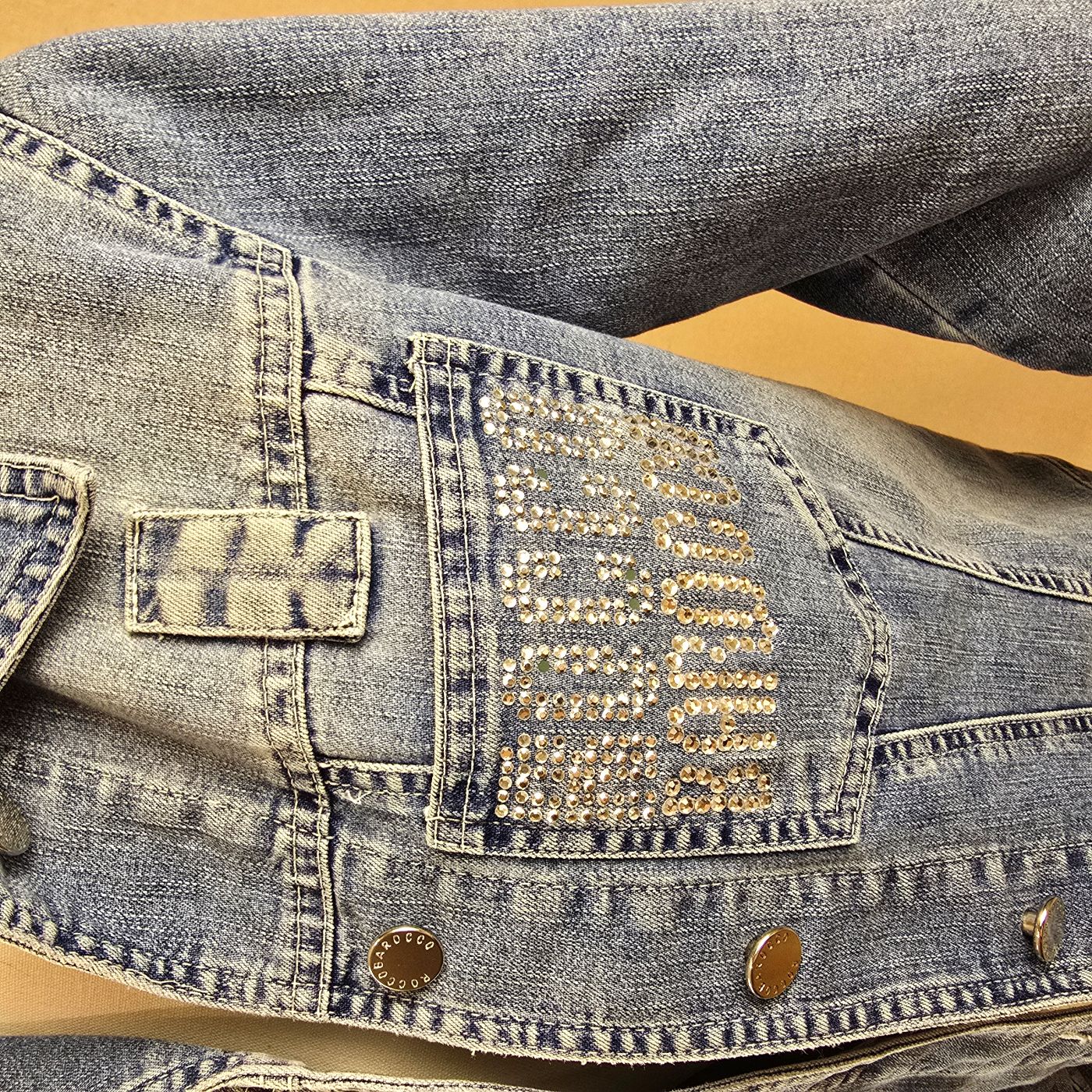 Detailansicht der Brusttasche mit glitzerndem Roccobarocco-Emblem auf der Vintage-Jeansjacke in Mittelblau