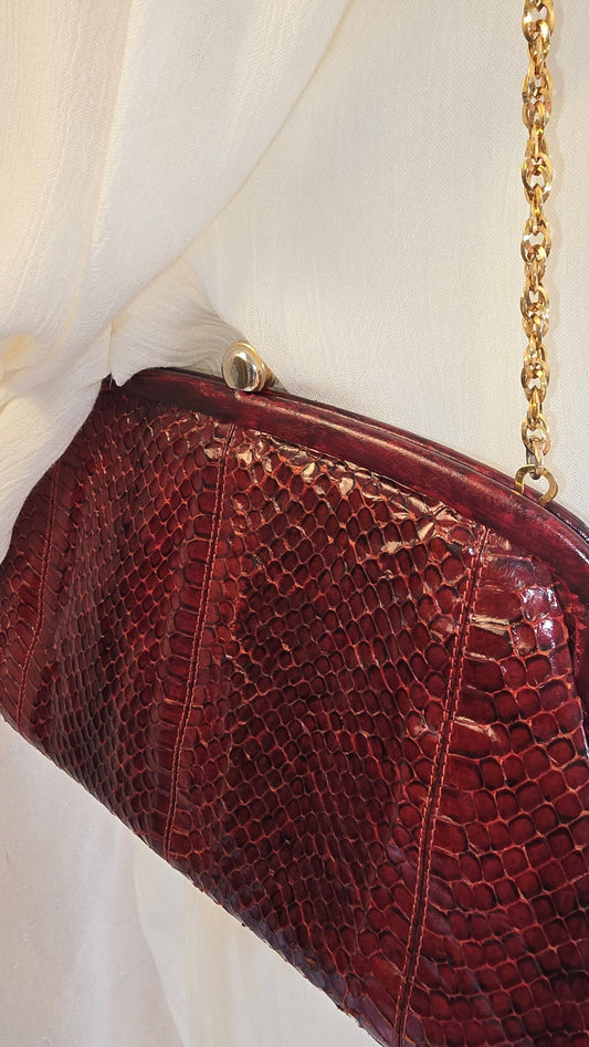 Vintage-Tasche in Bordeaux mit goldener Kette – getragen an cremefarbener Puppe, Detailaufnahme der Schlangenprägung