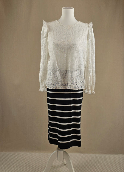 Weißes Spitzenshirt mit langen Ärmeln über einem schwarz-weiß gestreiften Rock – Vorderansicht auf Büste.