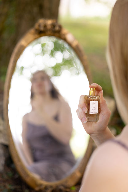 Anwendung von Aimée de Mars Lily Ambre im Freien vor einem Spiegel – blumig-warmer Naturduft mit Amber und Vanille