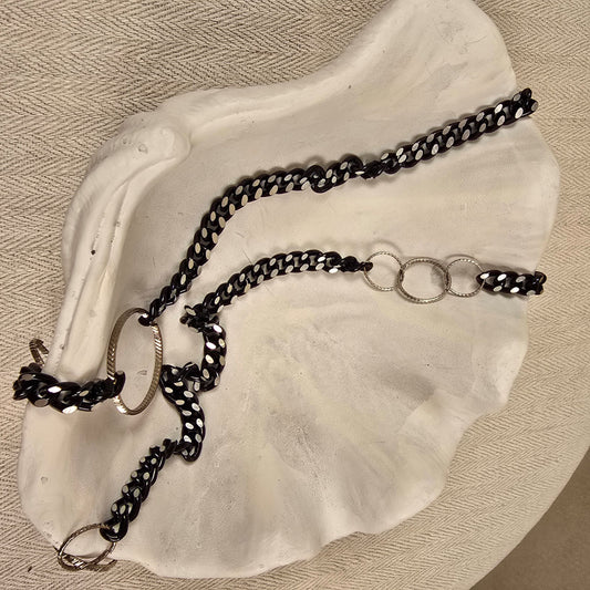 Halskette „Chain Reaction“ mit silberfarbenen Gliedern und schwarzem Stoffband mit weißen Punkten – auffälliger, flexibler Materialmix

