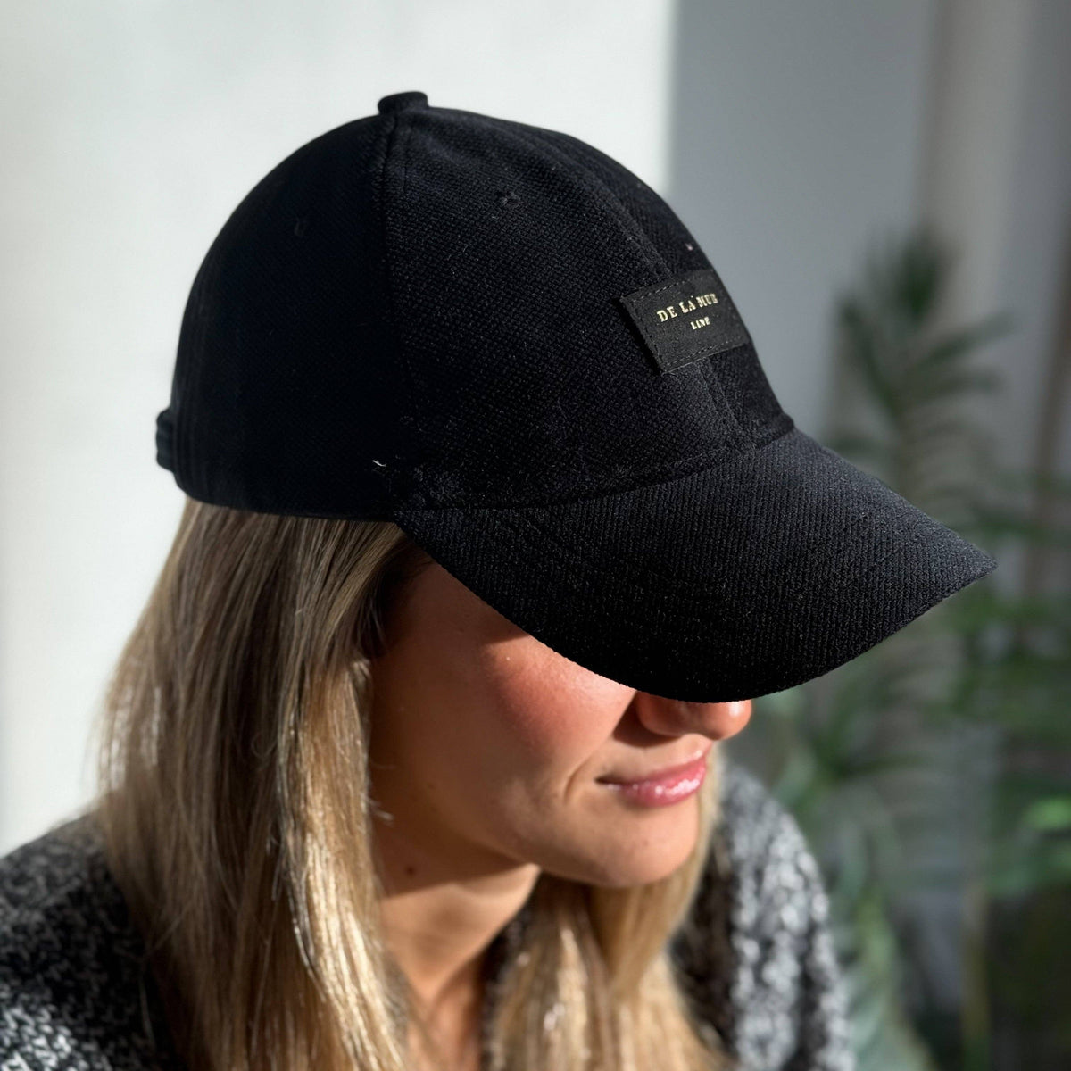 Model mit schwarzer De La Mur Aza Samtkappe mit gebogenem Schirm und Markenlabel mit goldenem Lurex
