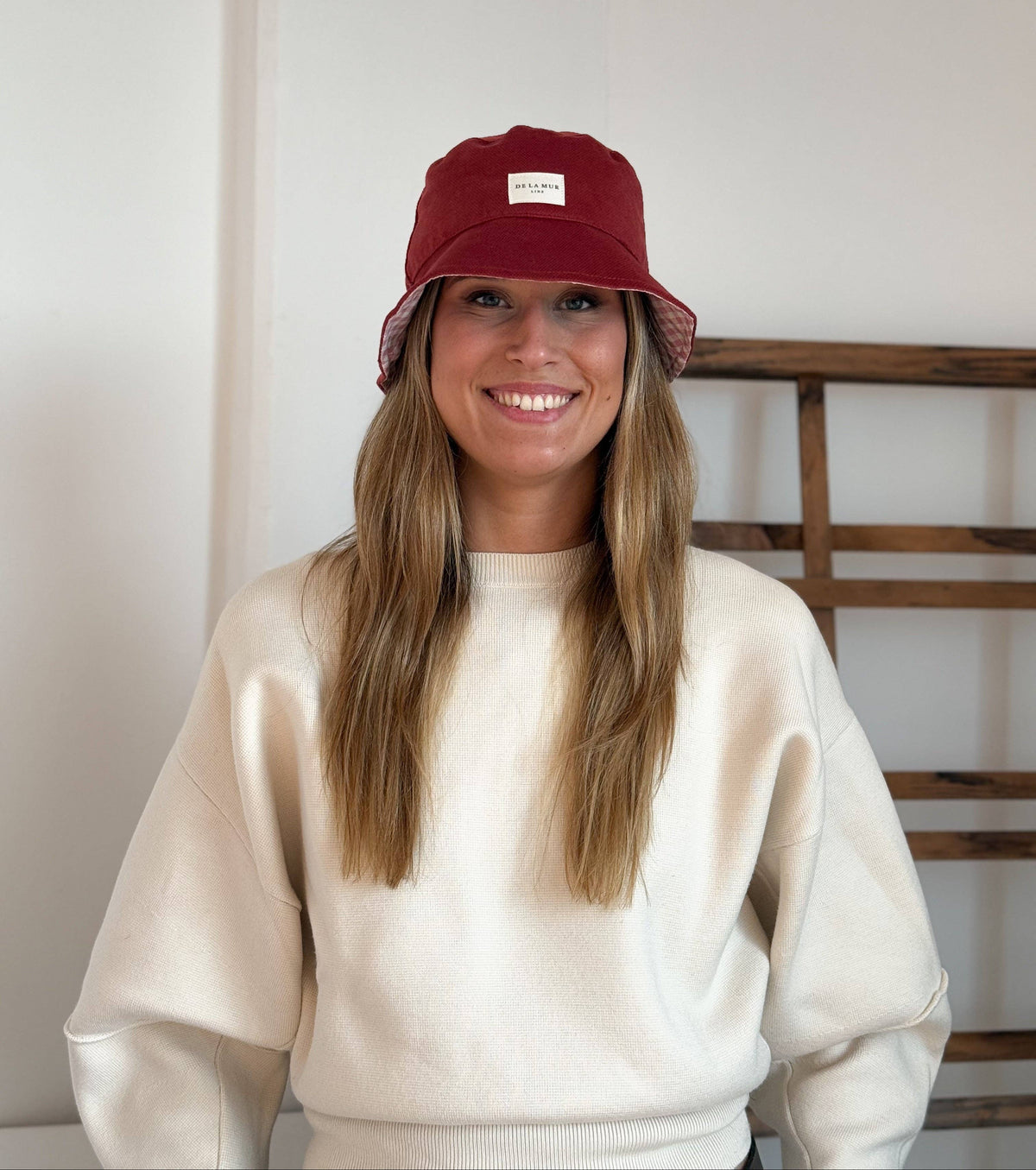 Model mit bordeauxrotem De La Mur Bore Bucket Hat aus Samt mit aufgenähtem Markenlabel