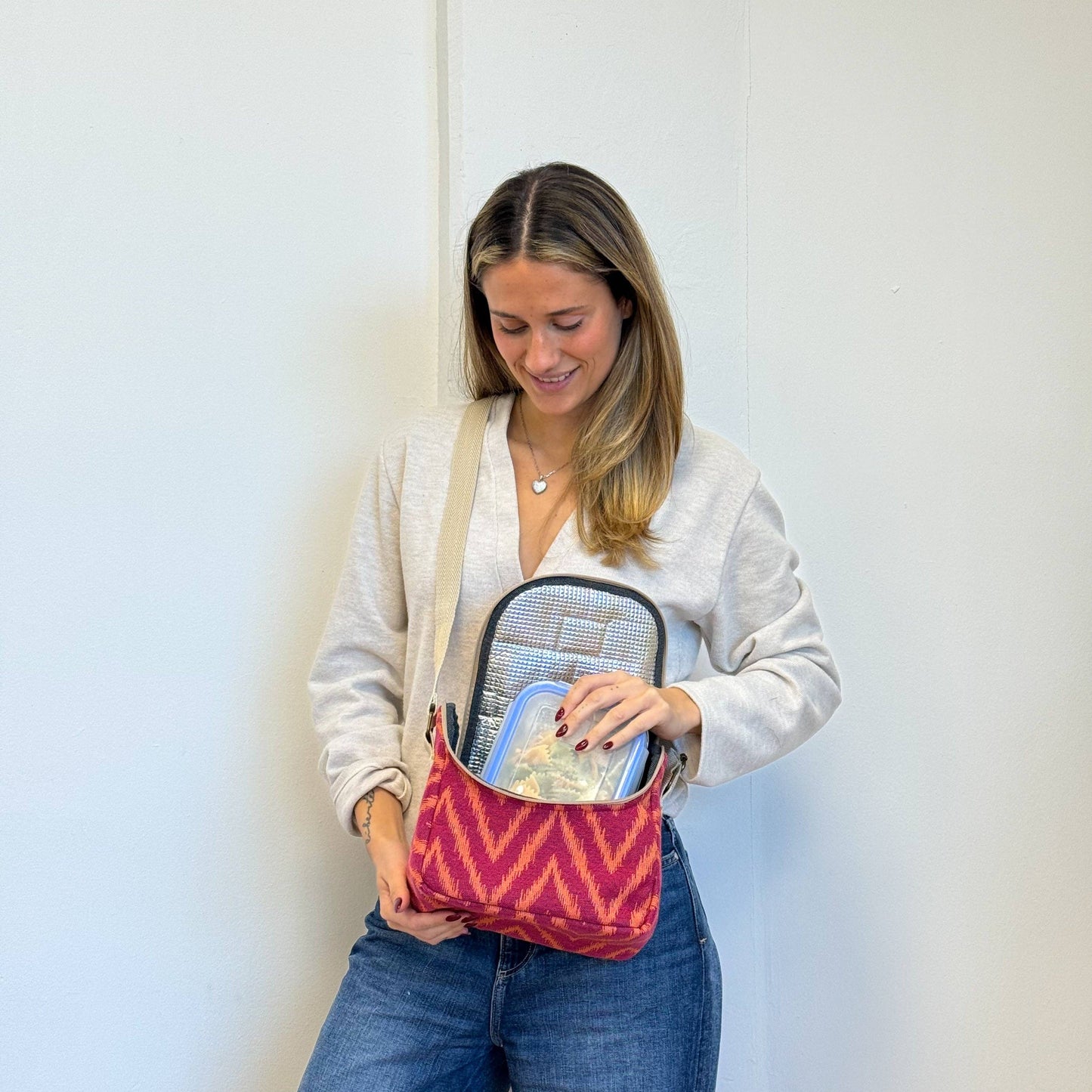 Isolierte Lunchtasche Fuego von De La Mur mit Zickzackmuster in Fuchsia und Orange vor weißem Hintergrund
