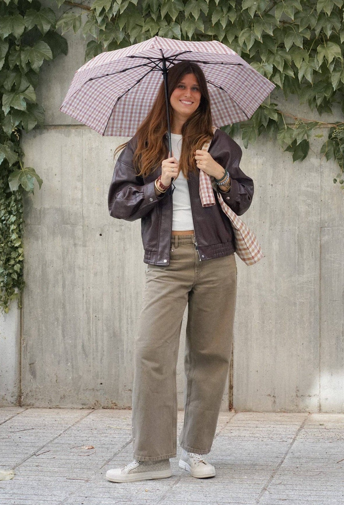 Model mit geöffnetem De La Mur Zia Taschenschirm mit Vichy-Karos in Ziegelrot und Beige
