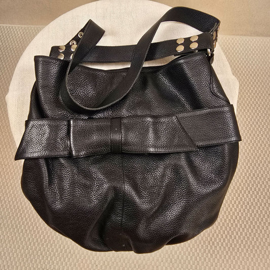 Schwarzer Ledershopper mit markanter Schleife und silbernen Nieten – edles Replikat im Stil von Armani, aus weichem, schwerem Leder, stilvoll inszeniert auf rundem, hellen Untergrund.